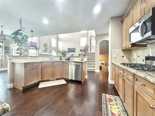 a kitchen with stainless steel appliances a stove a sink dishwasher a refrigerator and white cabinets with wooden floor