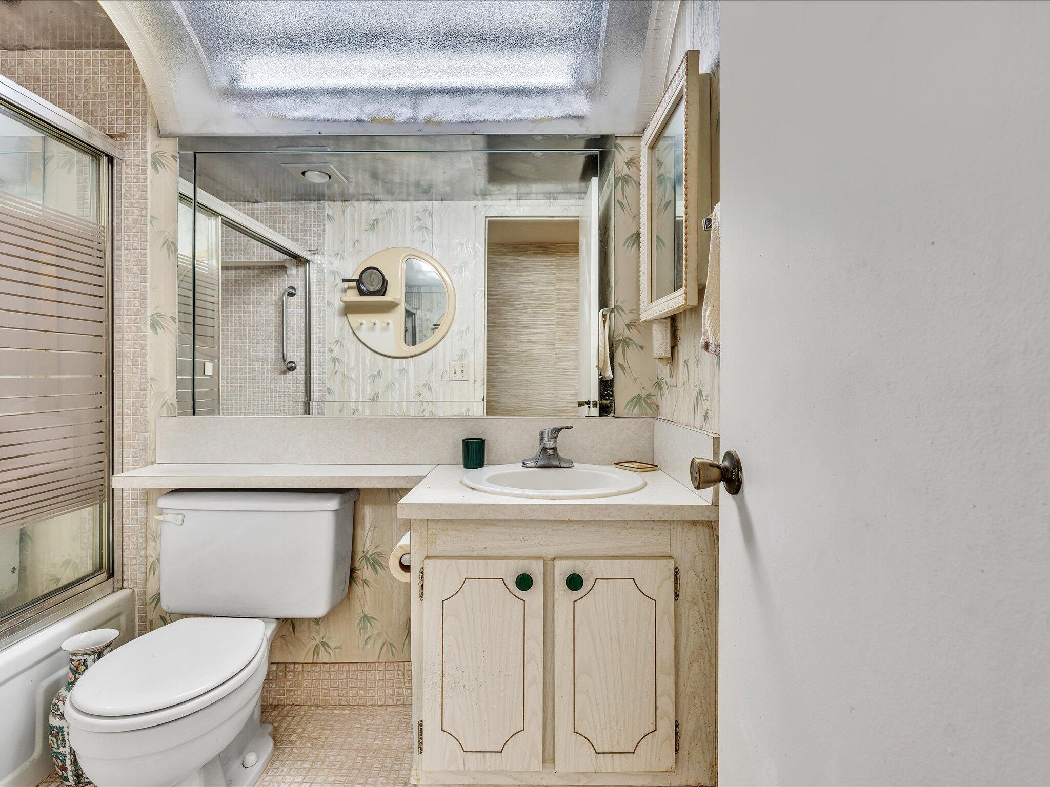 288 Fanshaw Drive, Unit G Boca Raton, FL 33434 - Photo 26 of 49 a bathroom with a toilet sink vanity and mirror