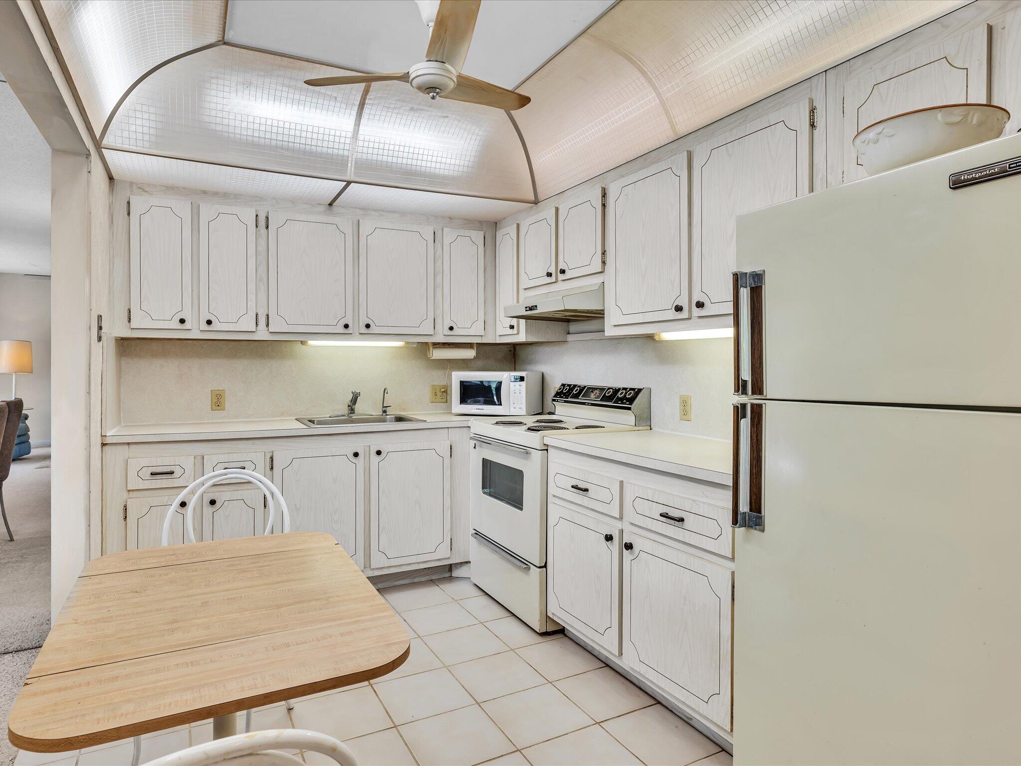 288 Fanshaw Drive, Unit G Boca Raton, FL 33434 - Photo 8 of 49 a kitchen with white cabinets and white appliances
