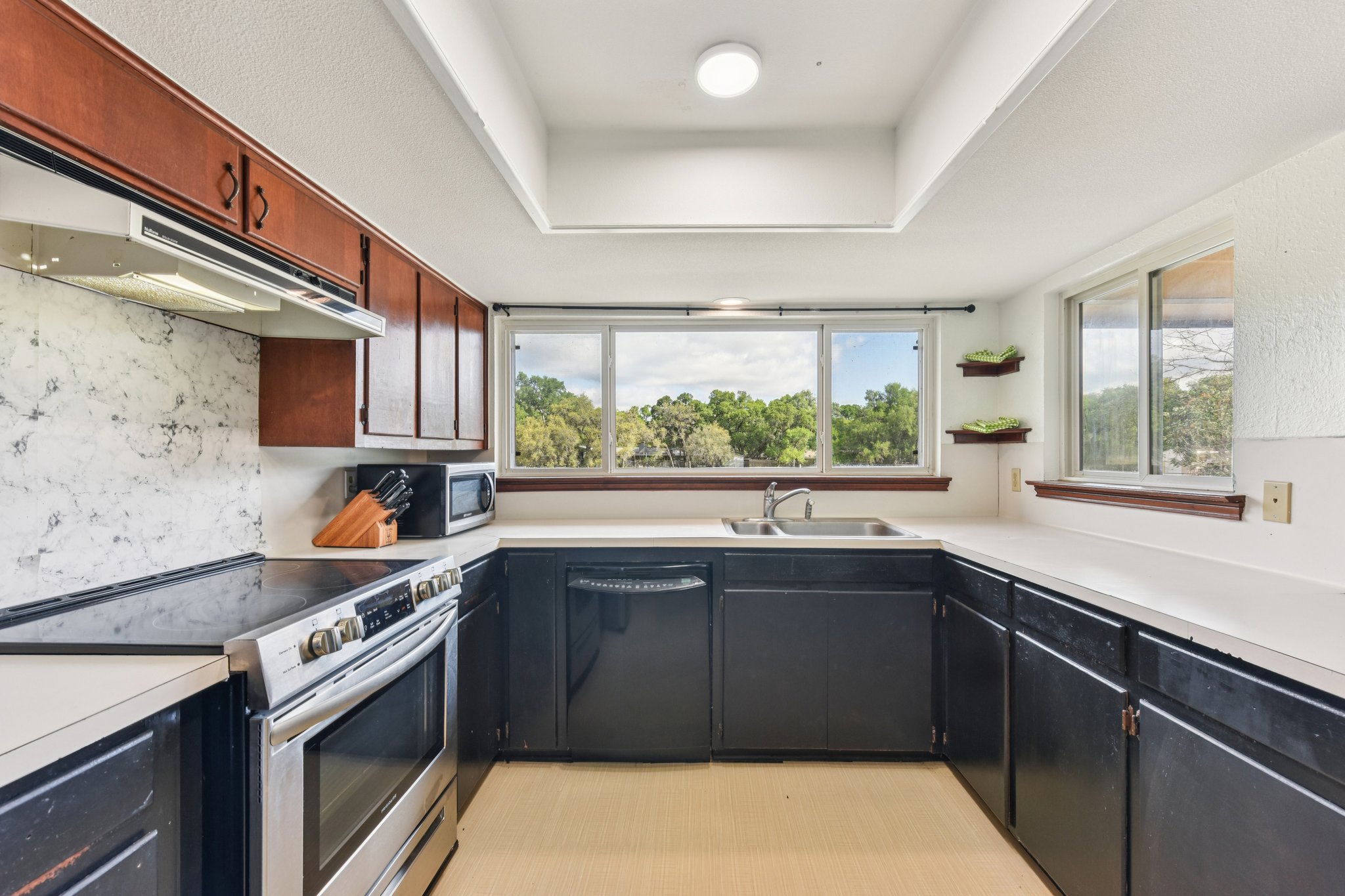 504 Buckaroo Trail Buda, TX 78610 - Photo 6 of 39 Kitchen with stainless steel appliances, dark cabinets, light countertops, and a raised ceiling