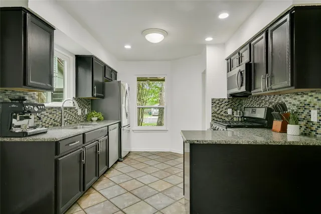 a kitchen with stainless steel appliances granite countertop a sink stove and cabinets