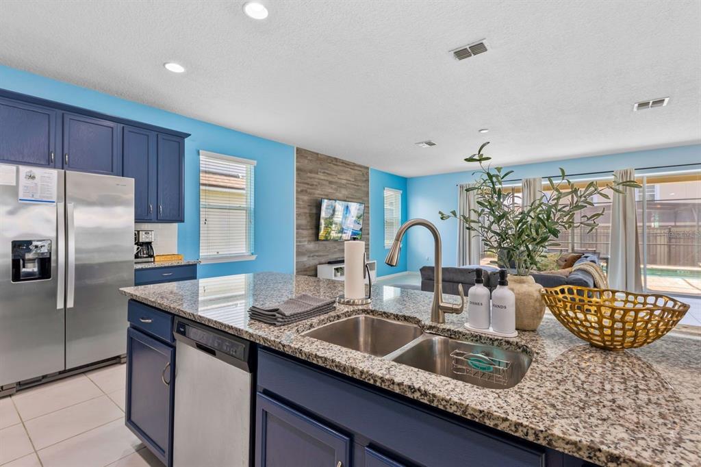9042 Sunshine Ridge Loop Kissimmee, FL 34747 - Photo 6 of 44 a kitchen with granite countertop a sink and a refrigerator