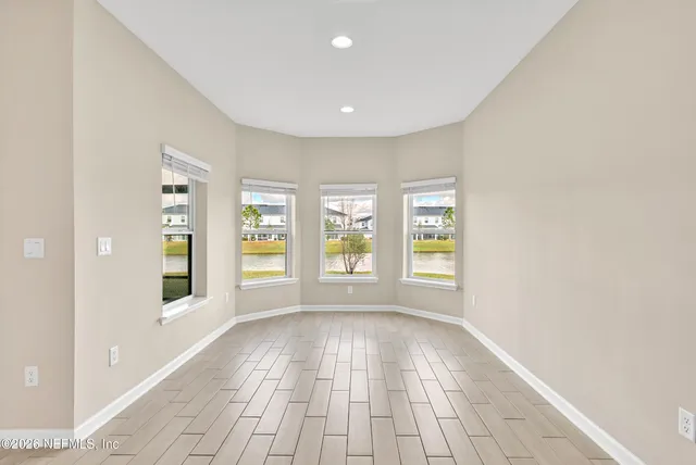 a view of empty room with wooden floor and windows
