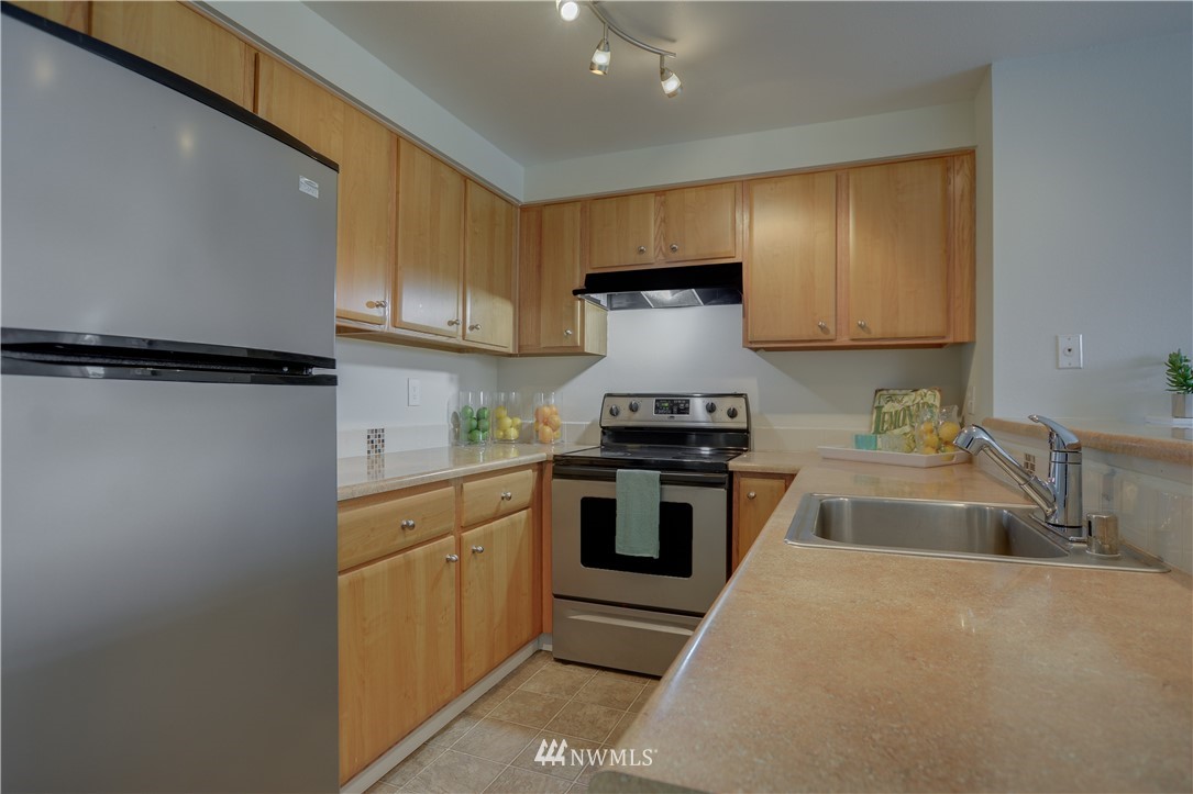 9200 Greenwood Avenue North, Unit 104 Seattle, WA 98103 - Photo 9 of 19 a kitchen with granite countertop a sink stainless steel appliances and cabinets