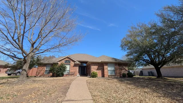 a view of a white house with a large tree in front of it