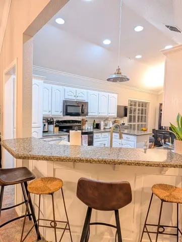 a kitchen with stainless steel appliances granite countertop a stove top oven a sink a dining table and chairs