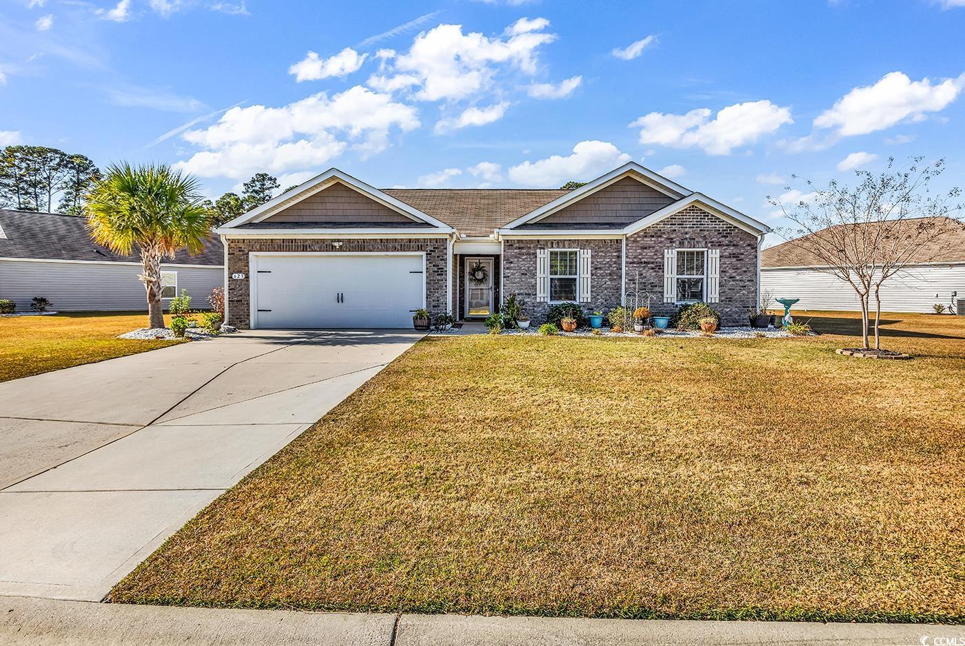 Craftsman house featuring driveway, a front lawn, and brick siding