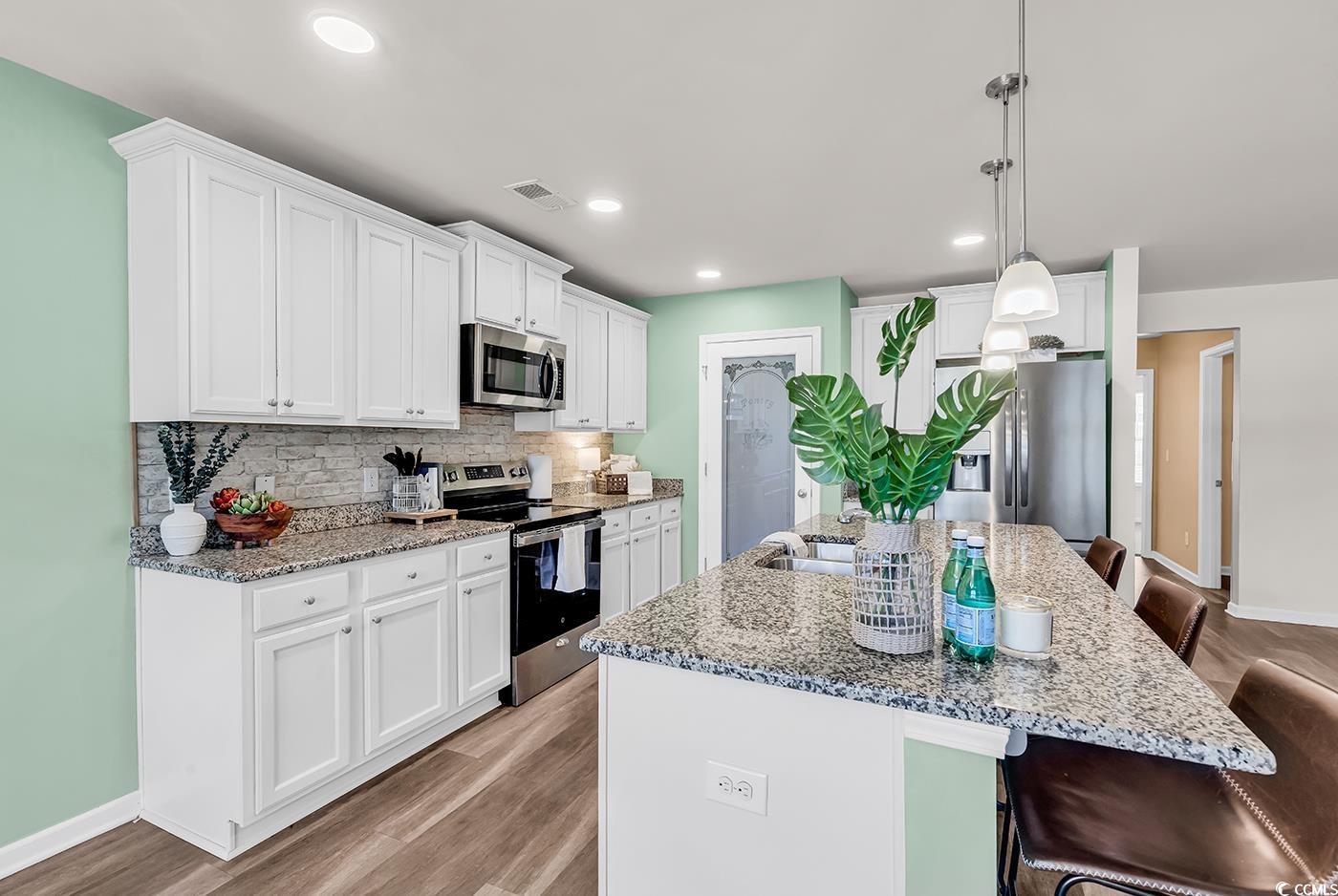 623 Burnt Ash Drive Longs, SC 29568 - Photo 5 of 35 Kitchen featuring a breakfast bar, appliances with stainless steel finishes, light wood finished floors, light stone counters, and recessed lighting