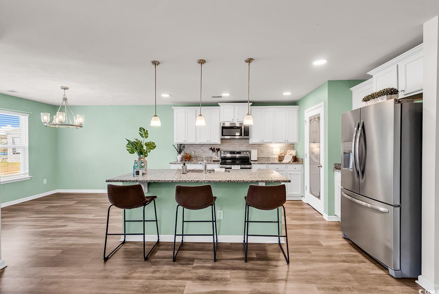 623 Burnt Ash Drive Longs, SC 29568 - Photo 8 of 35 Kitchen featuring stainless steel appliances, white cabinets, decorative backsplash, an island with sink, and decorative light fixtures