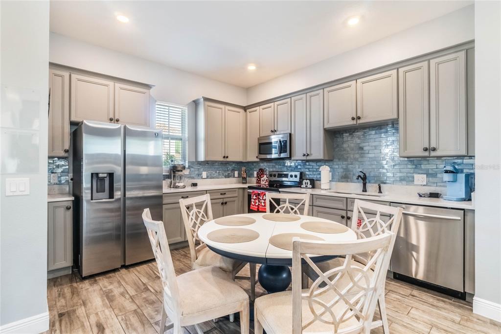 8008 Sandy Toes Way Kissimmee, FL 34747 - Photo 5 of 21 a kitchen with stainless steel appliances a table chairs refrigerator and a sink