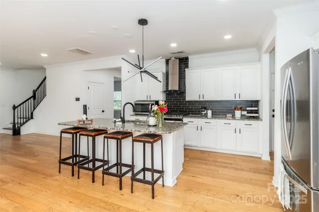 a kitchen with stainless steel appliances kitchen island a table chairs in it and wooden floors