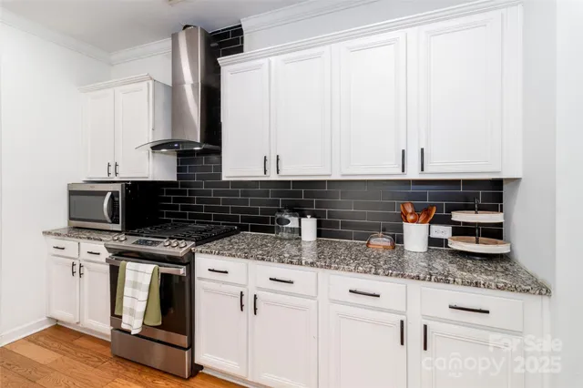 a kitchen with stainless steel appliances granite countertop a stove a sink and white cabinets