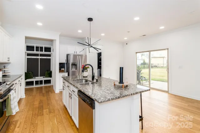a kitchen with stainless steel appliances granite countertop a sink a stove and a wooden floors
