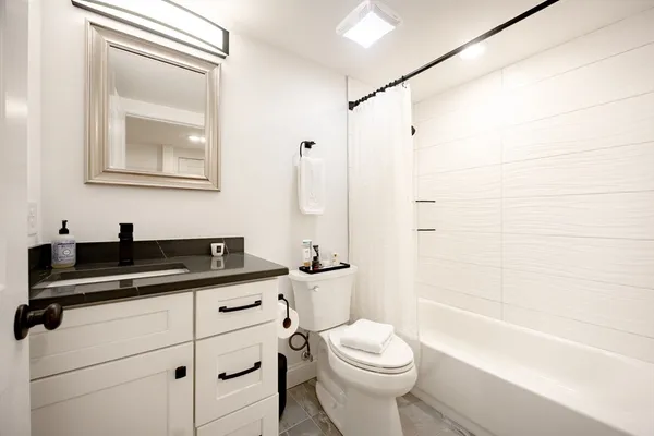 a bathroom with a granite countertop sink a toilet a mirror and shower