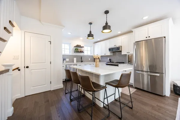 a kitchen with stainless steel appliances a refrigerator a stove a sink and chairs