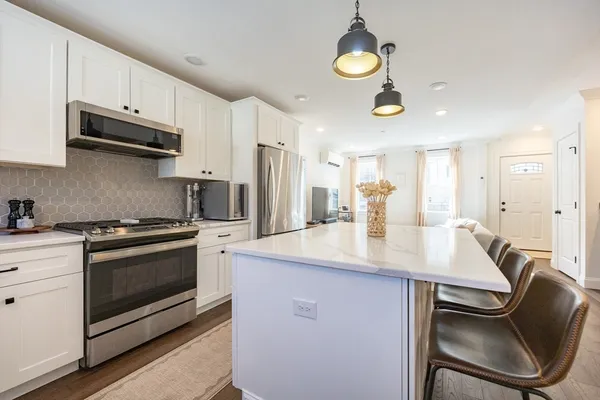 a kitchen with stainless steel appliances granite countertop a sink a stove a refrigerator cabinets and chairs