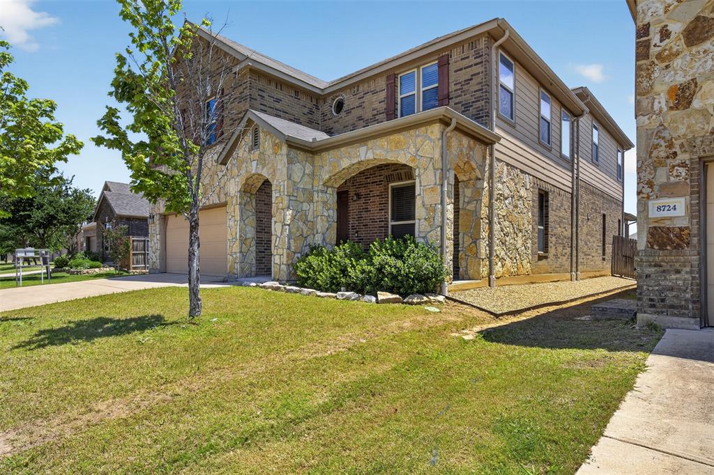 8728 Maple Ridge Trail Fort Worth, TX 76244 - Photo 2 of 40 Stone and brick facade featuring an arched entry, multiple windows with brown shutters, and a two-car garage with a concrete driveway