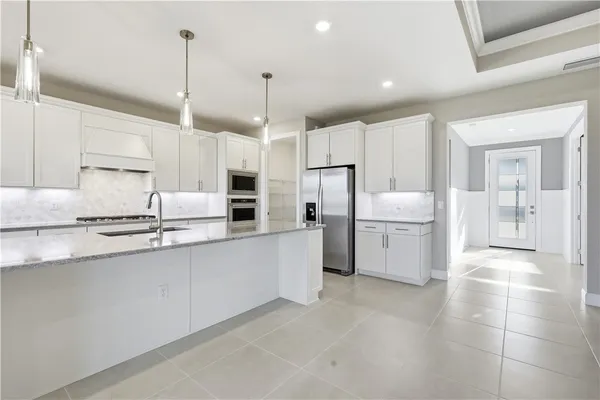 a kitchen with granite countertop a sink a counter space appliances and cabinets