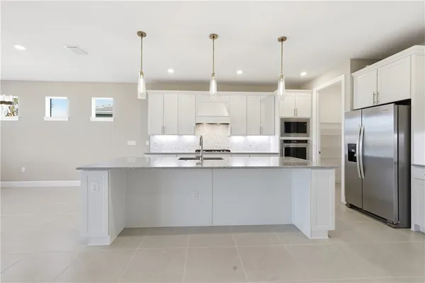 a kitchen with stainless steel appliances granite countertop a refrigerator a sink and a oven