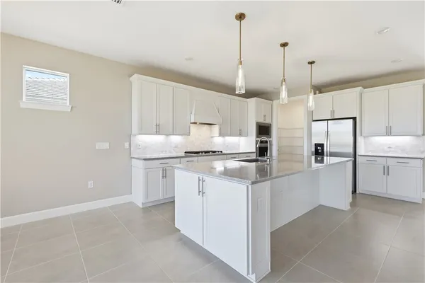 a kitchen with stainless steel appliances granite countertop a sink a stove a refrigerator and white cabinets
