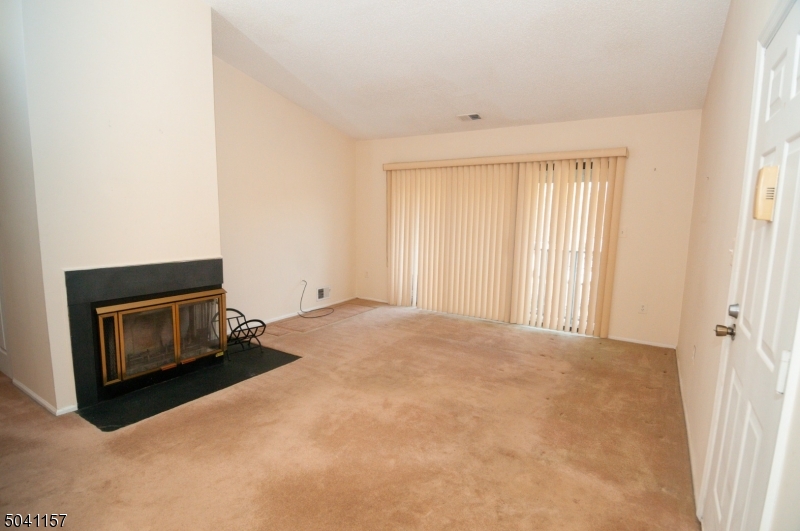 a view of an empty room with a fireplace and a window