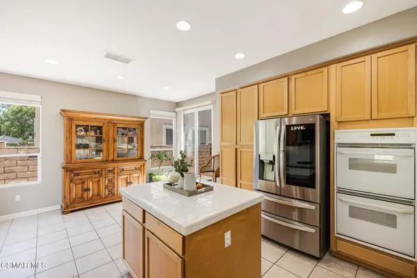 a kitchen that has a lot of white cabinets and stainless steel appliances