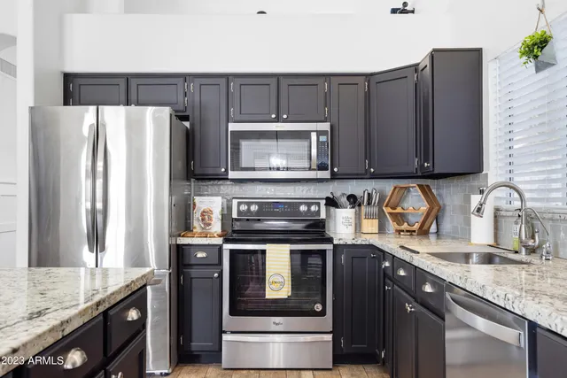 a kitchen with granite countertop a stove microwave and refrigerator