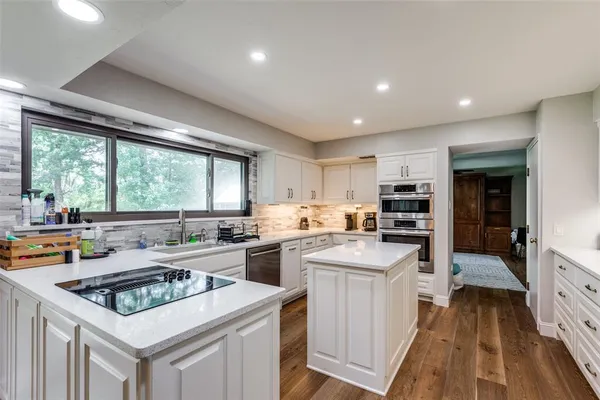 a kitchen with a stove a sink dishwasher and a refrigerator with wooden floor