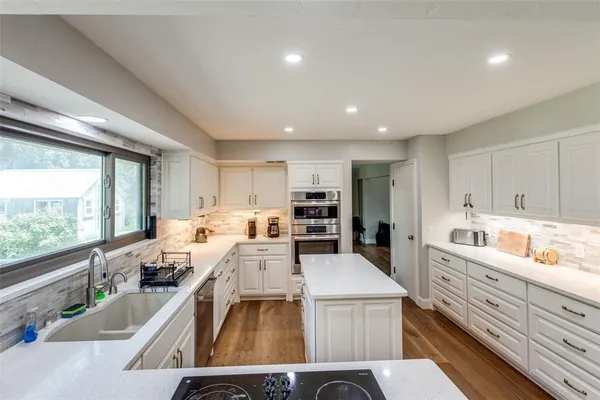 a kitchen that has a lot of cabinets a sink and appliances in it
