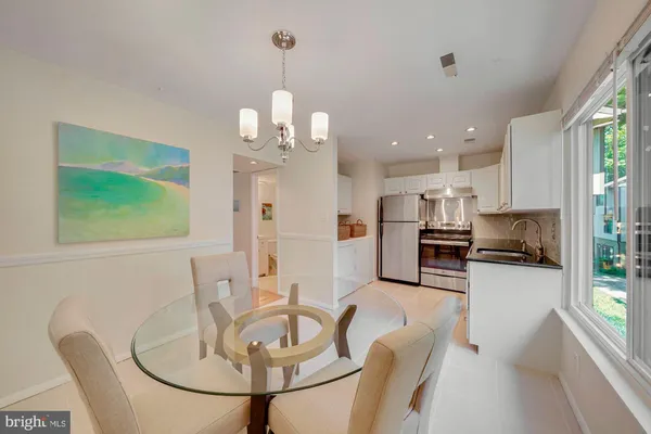 a kitchen with stainless steel appliances kitchen island granite countertop a sink a stove a dining table and chairs with wooden floor