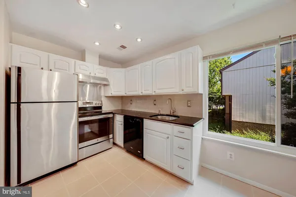 a kitchen with granite countertop white cabinets and stainless steel appliances