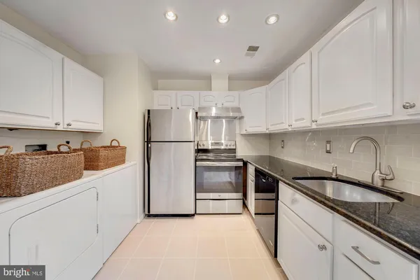 a kitchen with granite countertop white cabinets and stainless steel appliances