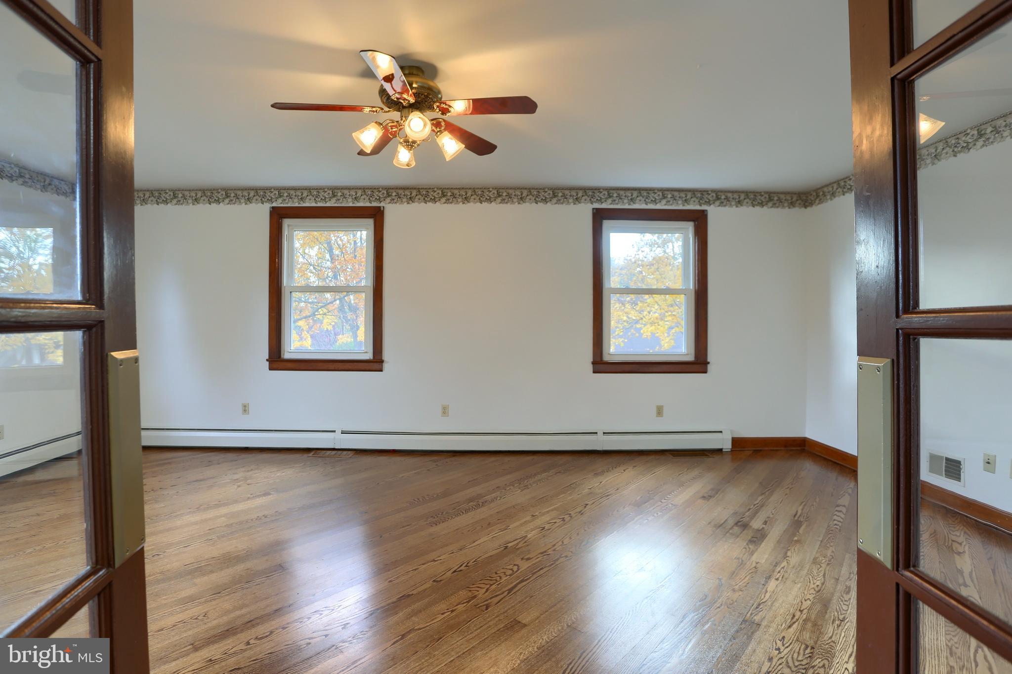 338 Locust Street Halifax, PA 17032 - Photo 5 of 43 an empty room with wooden floor chandelier fan and windows