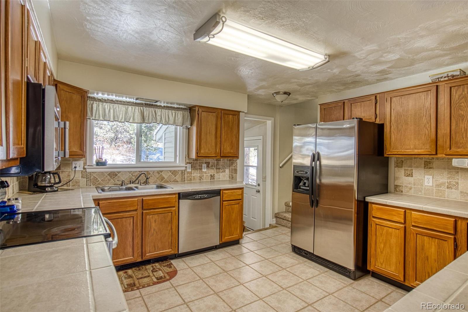 25681 Mosier Circle Conifer, CO 80433 - Photo 16 of 29 a kitchen with stainless steel appliances granite countertop a sink stove and refrigerator