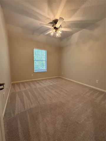 an empty room with windows and fan