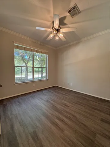 an empty room with wooden floor chandelier fan and windows