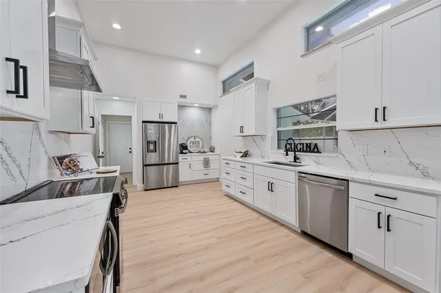 a large kitchen with stainless steel appliances lots of counter space sink refrigerator and cabinets