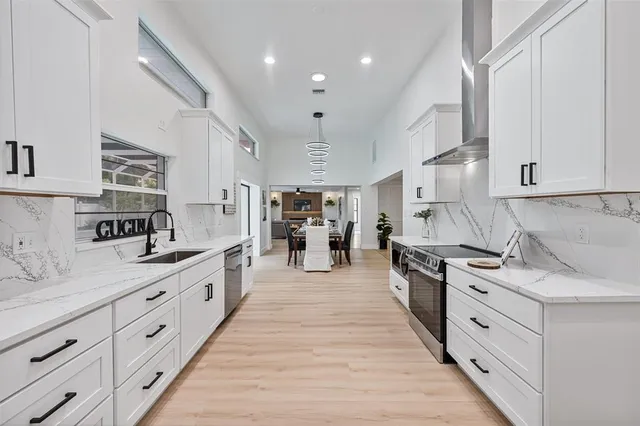 a large kitchen with stainless steel appliances granite countertop a stove oven and a white cabinets