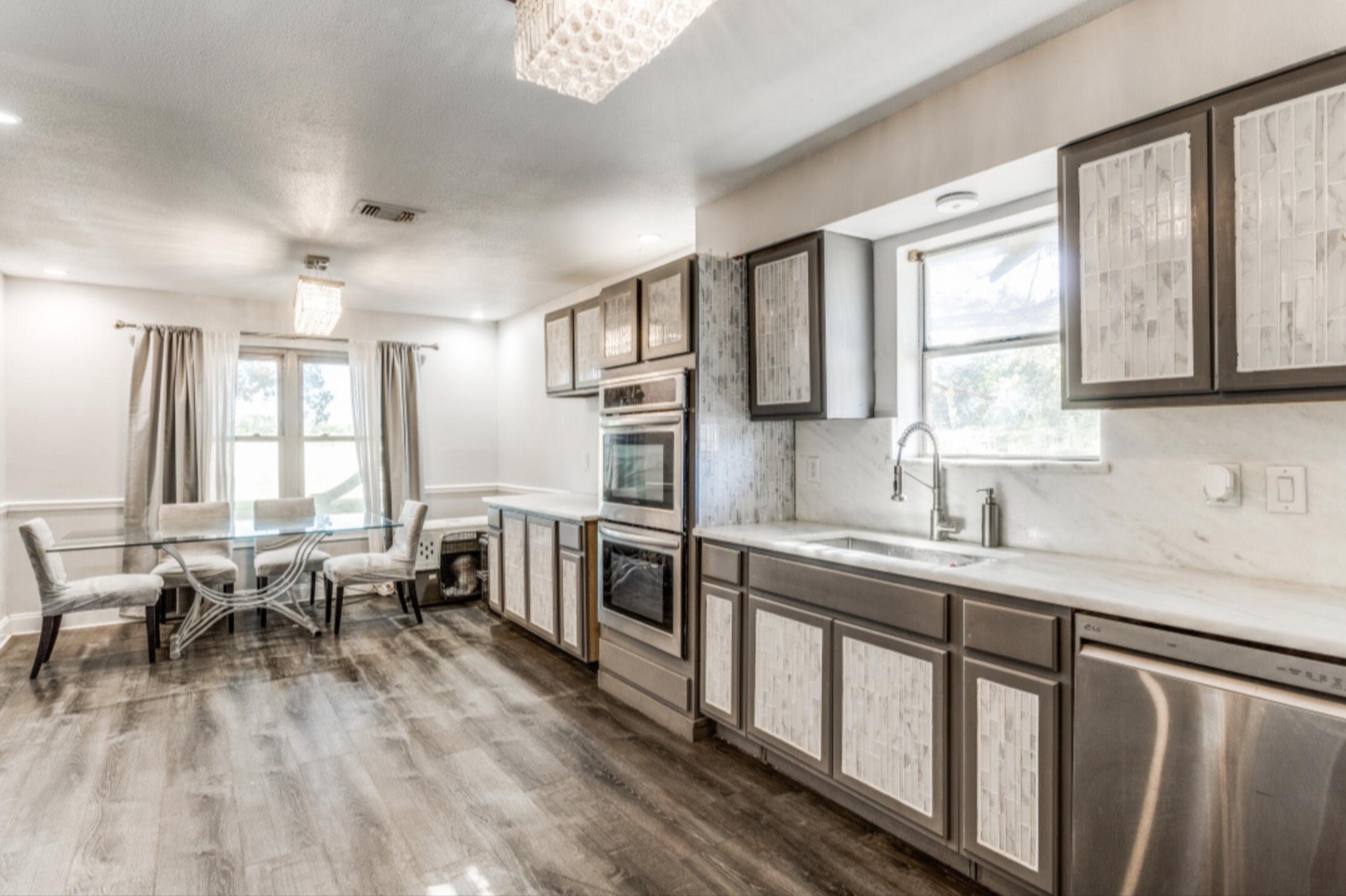 610 Pleasant Grove Road Elgin, TX 78621 - Photo 10 of 25 Kitchen featuring stainless steel appliances, light countertops, dark wood-type flooring, decorative backsplash, and glass insert cabinets