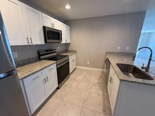 a kitchen with granite countertop a sink a stove and microwave