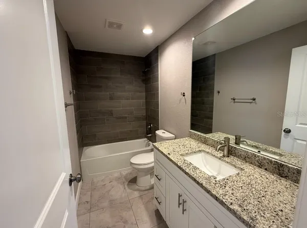 a bathroom with a granite countertop sink a toilet and shower