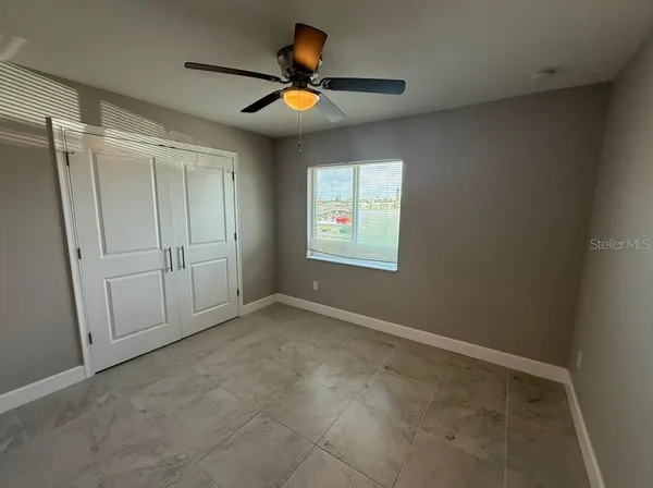 an empty room with ceiling fan and windows