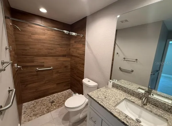 a bathroom with a granite countertop sink toilet and shower