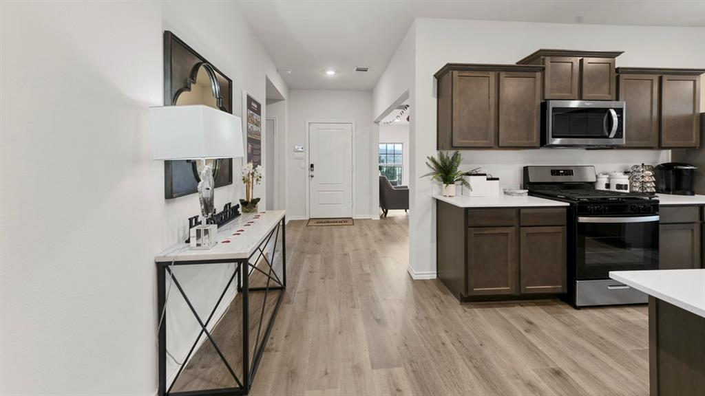 1671 Mantle Road Crandall, TX 75114 - Photo 5 of 24 Open-concept kitchen and entryway featuring wood-finish flooring, dark wood cabinetry, stainless steel appliances, and light countertops