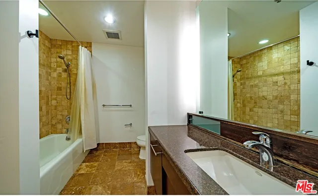 a bathroom with a granite countertop sink a mirror a bathtub and shower