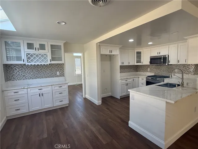 a kitchen with stainless steel appliances sink stove refrigerator and wooden floor