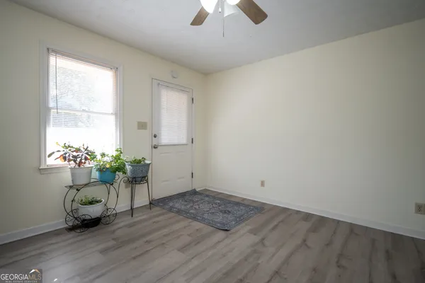 an empty room with wooden floor a chandelier fan and windows