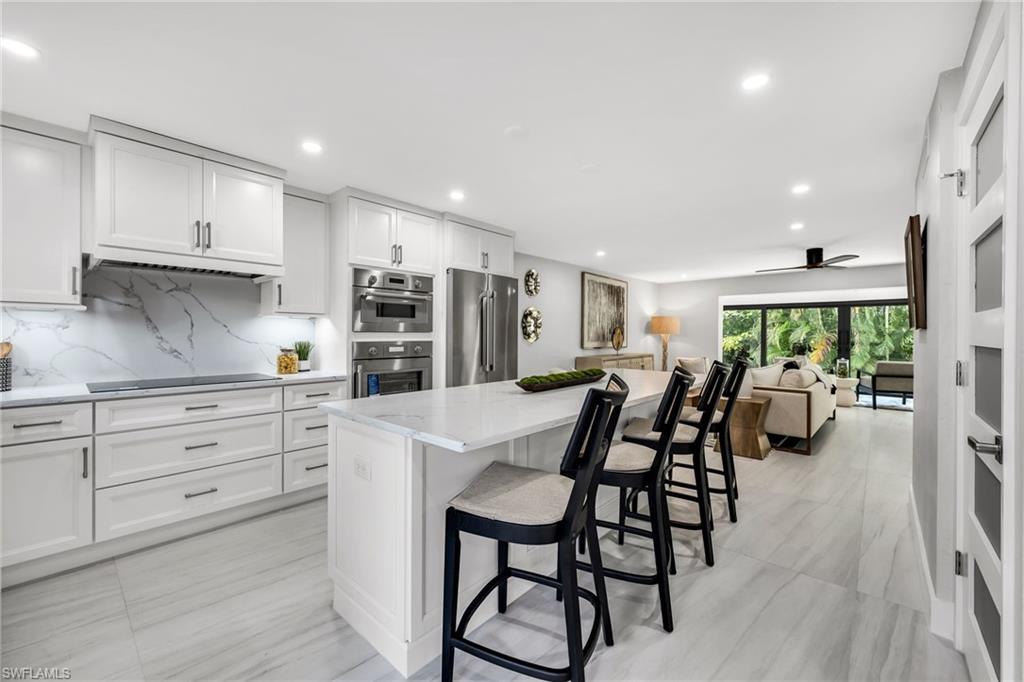 990 8th Street South, Unit 1C Naples, FL 34102 - Photo 1 of 24 a kitchen with stainless steel appliances kitchen island granite countertop a table chairs sink and cabinets