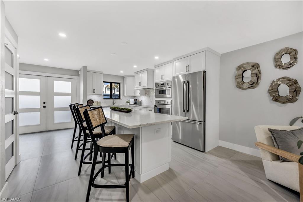 990 8th Street South, Unit 1C Naples, FL 34102 - Photo 4 of 24 a kitchen with a refrigerator a dining table and chairs