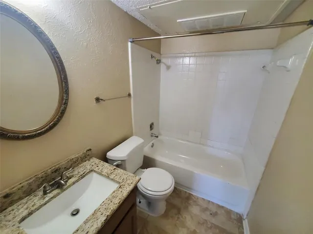 a bathroom with a granite countertop sink toilet a mirror and shower